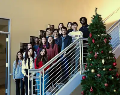 JA Alumni and JA Company Program students standing on a staircase during the holiday season.